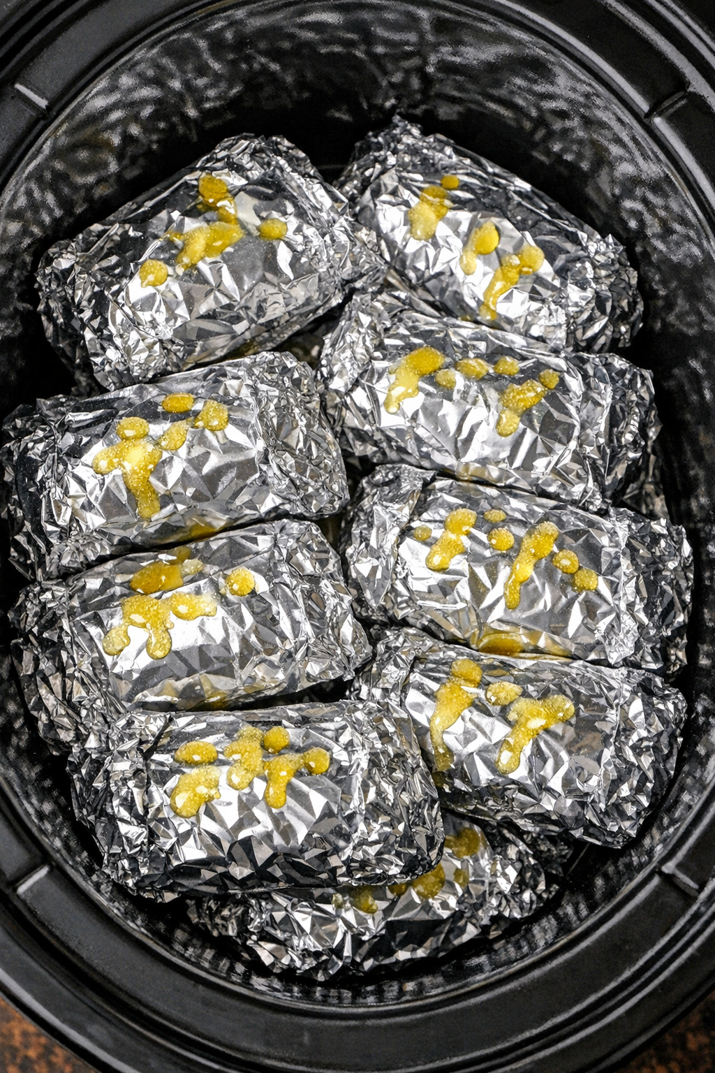 Slow cooker foil hot dog pasta packets in a black slow cooker