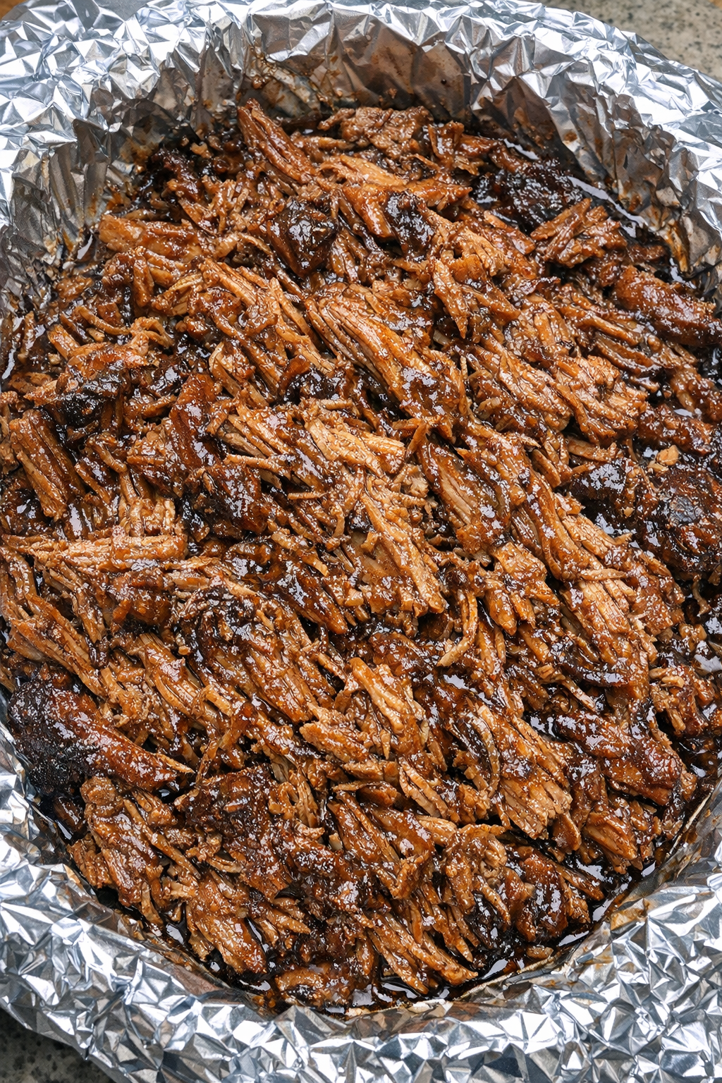 Finished root beer pulled pork in a foil-lined platter