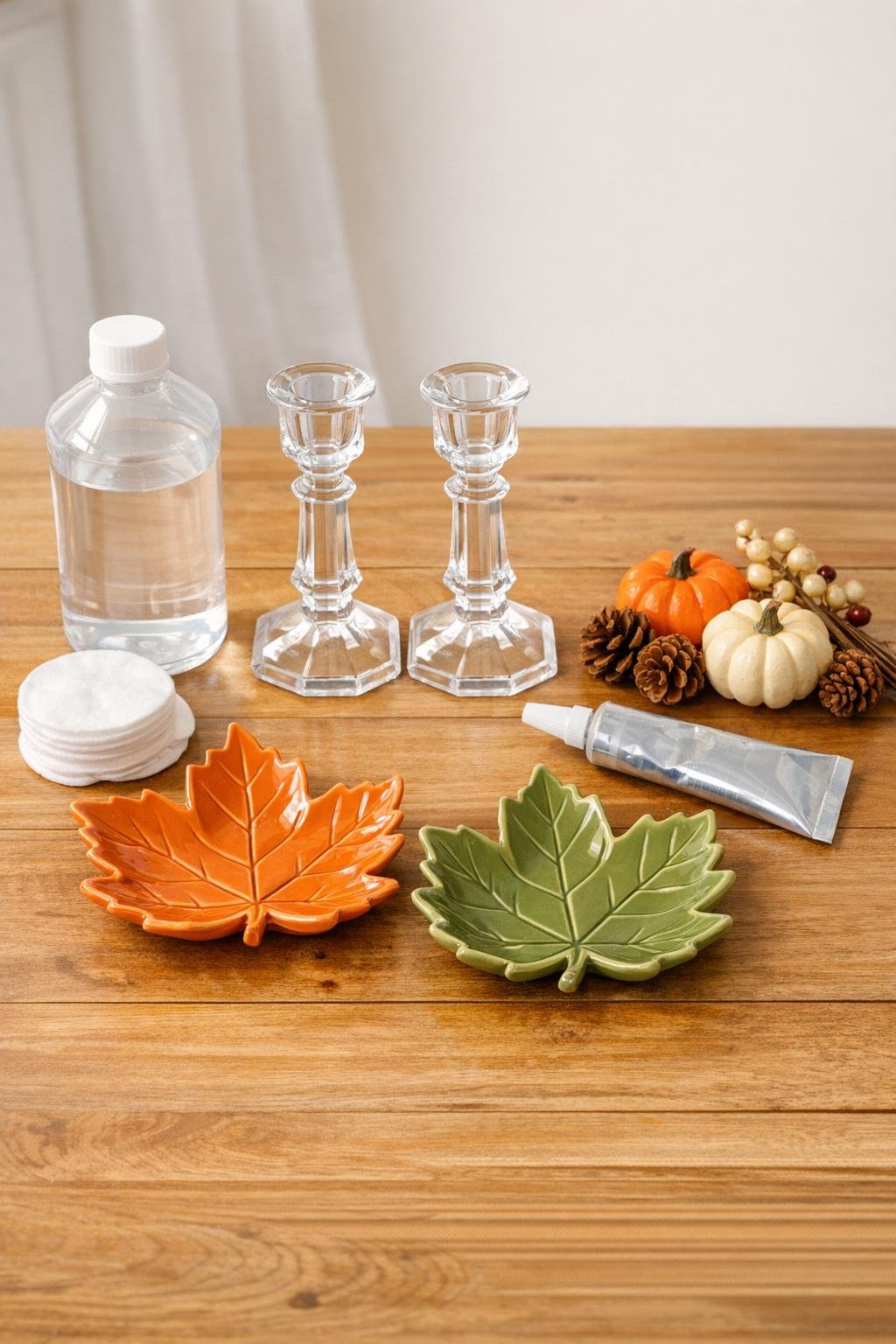 Dollar store ceramic leaf dishes, thrifted glass candlesticks, adhesive, and fall decorating supplies laid out together