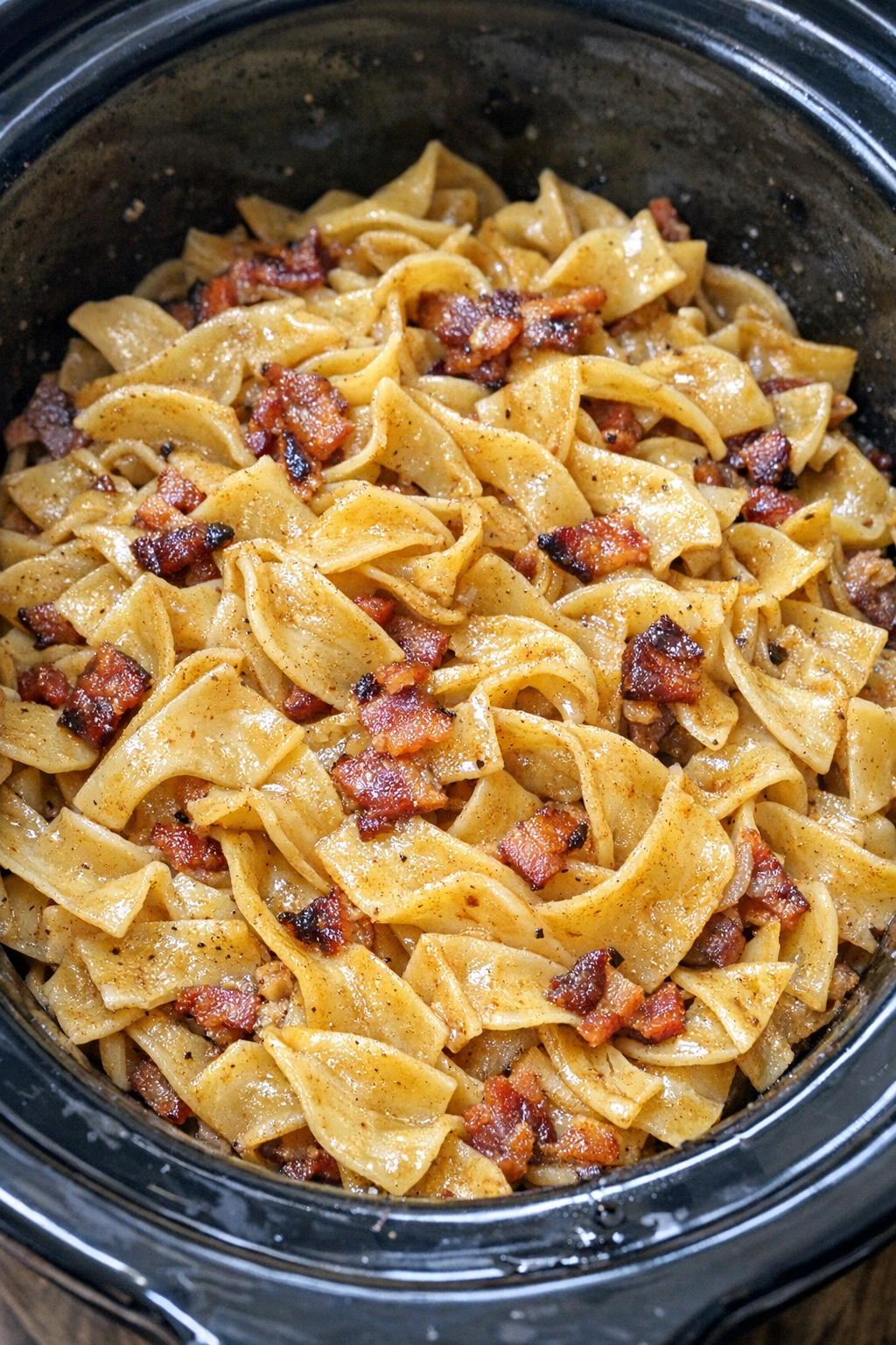 Slow cooker Amish bacon dripping noodles in a black slow cooker
