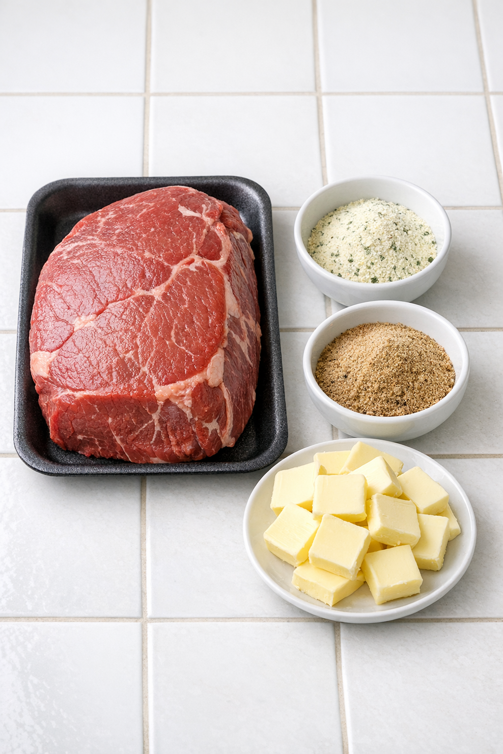 Beef roast, seasoning packets, and butter pats laid out for the recipe