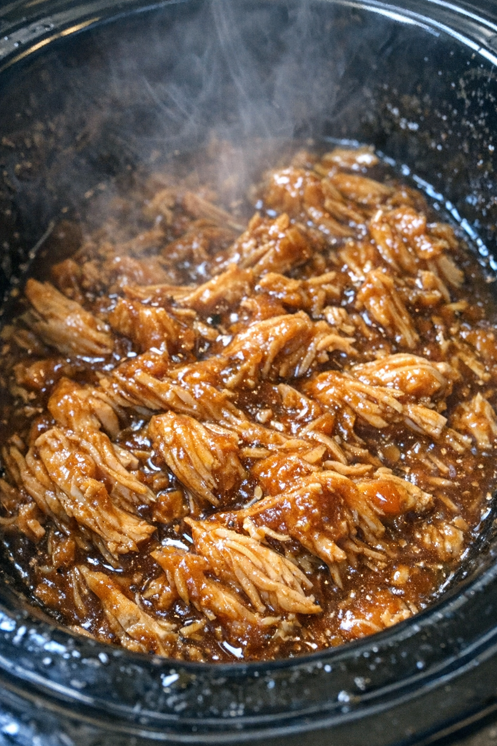 Succulent shredded protein in amber glaze in a slow cooker