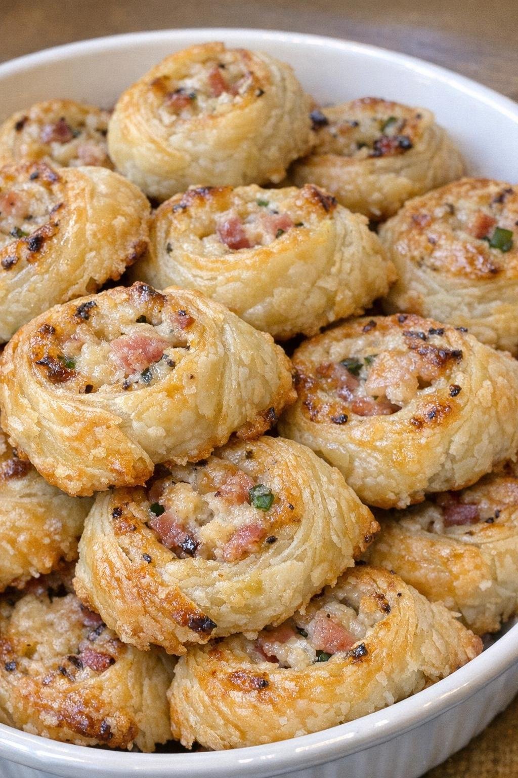 Golden flaky savory party pinwheels in a serving dish