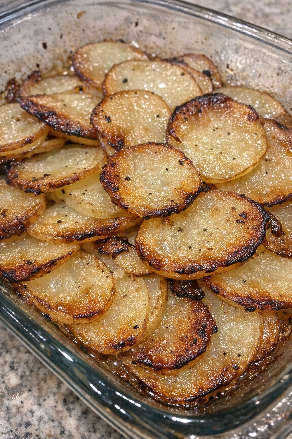 Golden crispy sliced potato casserole in a glass baking dish