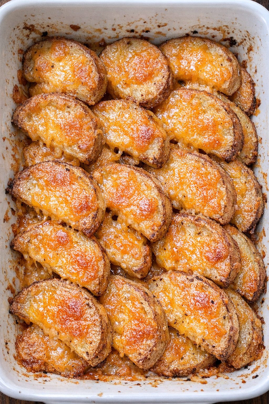 Half-moon shaped golden potato bites with melted cheddar in a casserole dish