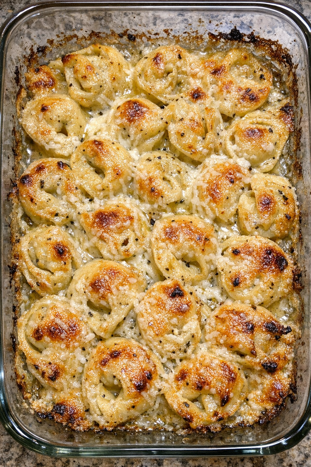 Golden cheese tortellini in garlic butter sauce baked in a glass dish