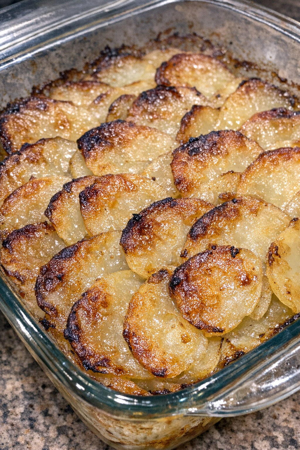 Golden brown scalloped potatoes in a glass baking dish