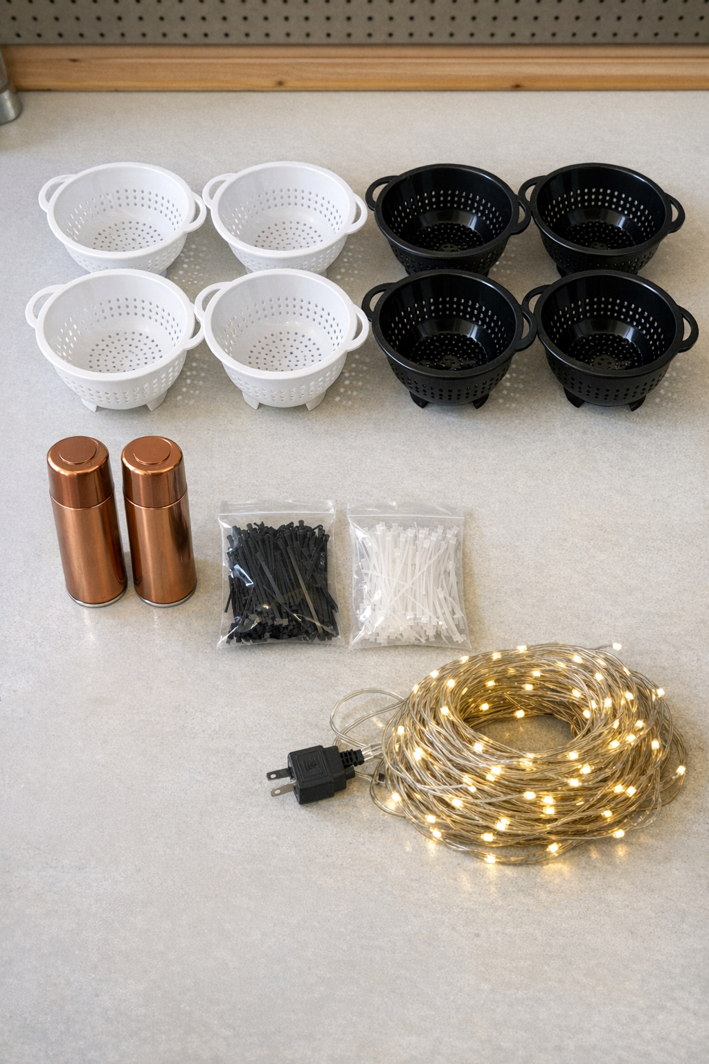 Copper spray paint, plastic colanders, zip ties, and warm white LED string lights laid out together