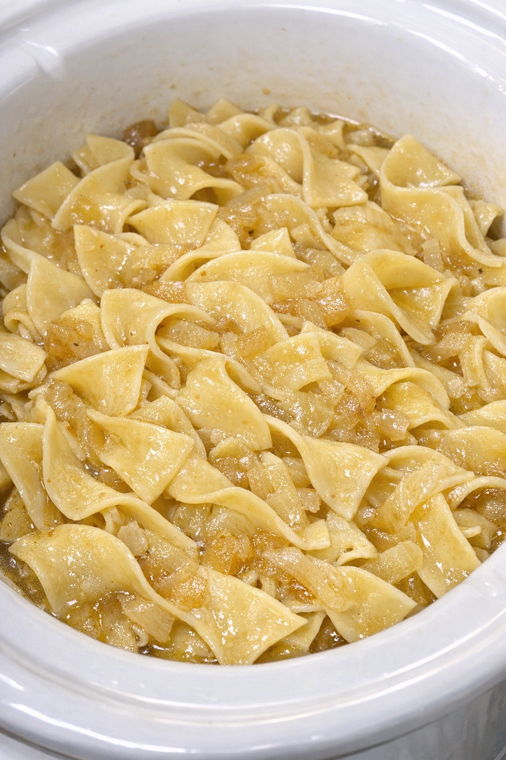 Slow cooker Amish onion noodles in a white slow cooker