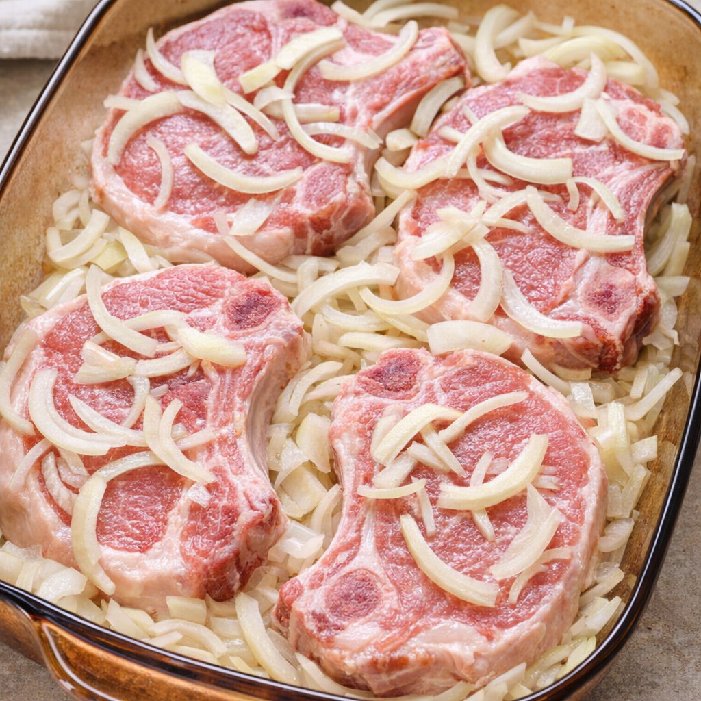 Sliced onion scattered over pork chops before baking