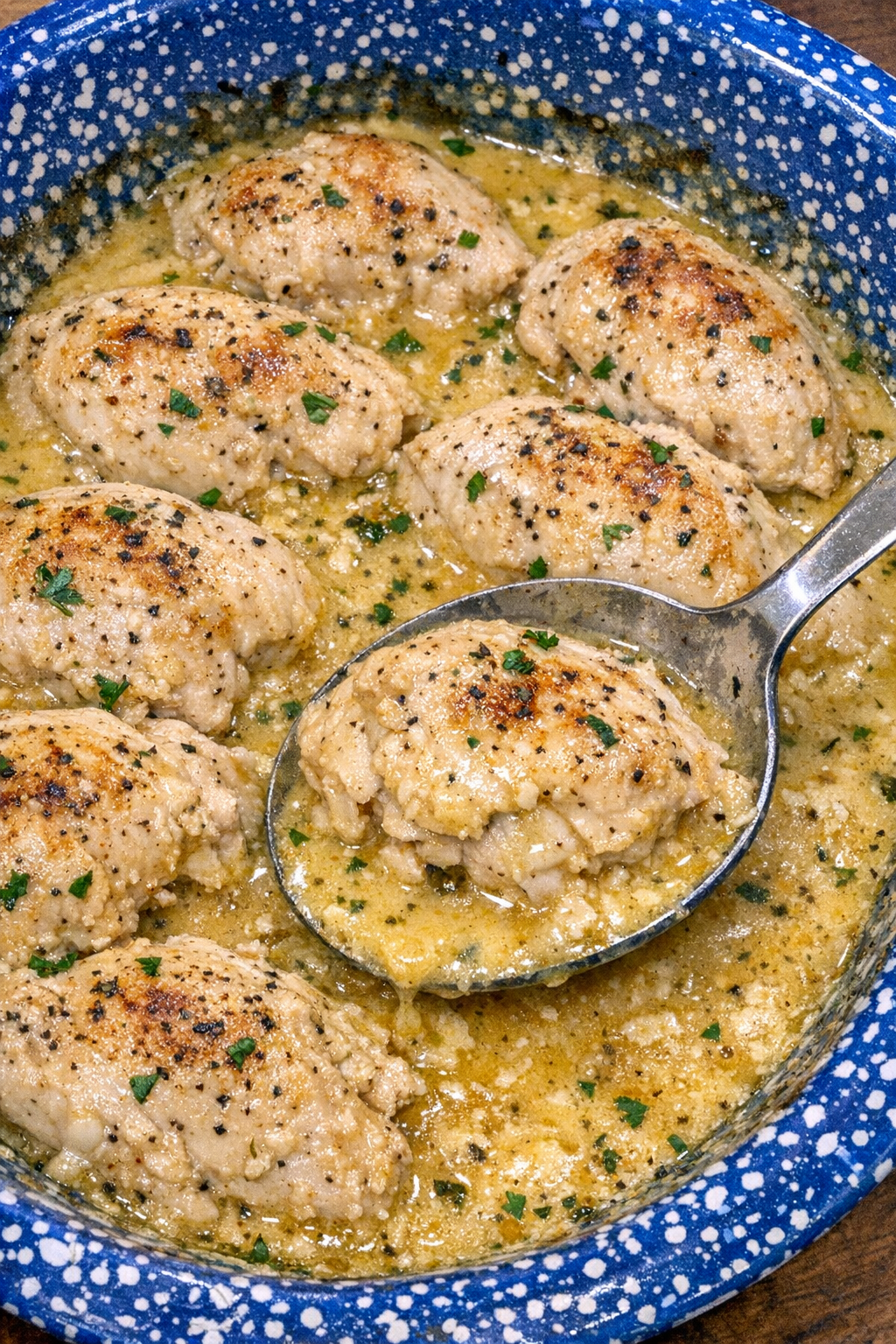 Tender chicken in creamy golden sauce in a blue speckled casserole dish