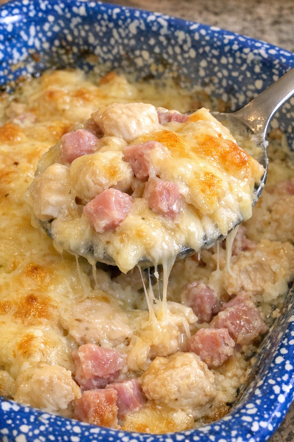 Golden bubbly chicken cordon bleu casserole in a blue speckled dish