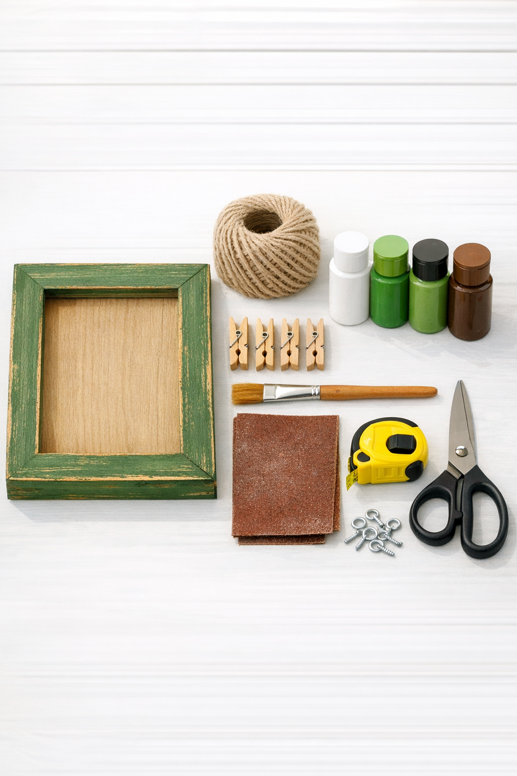 Materials for a painted wooden frame herb drying rack laid out on a worktable