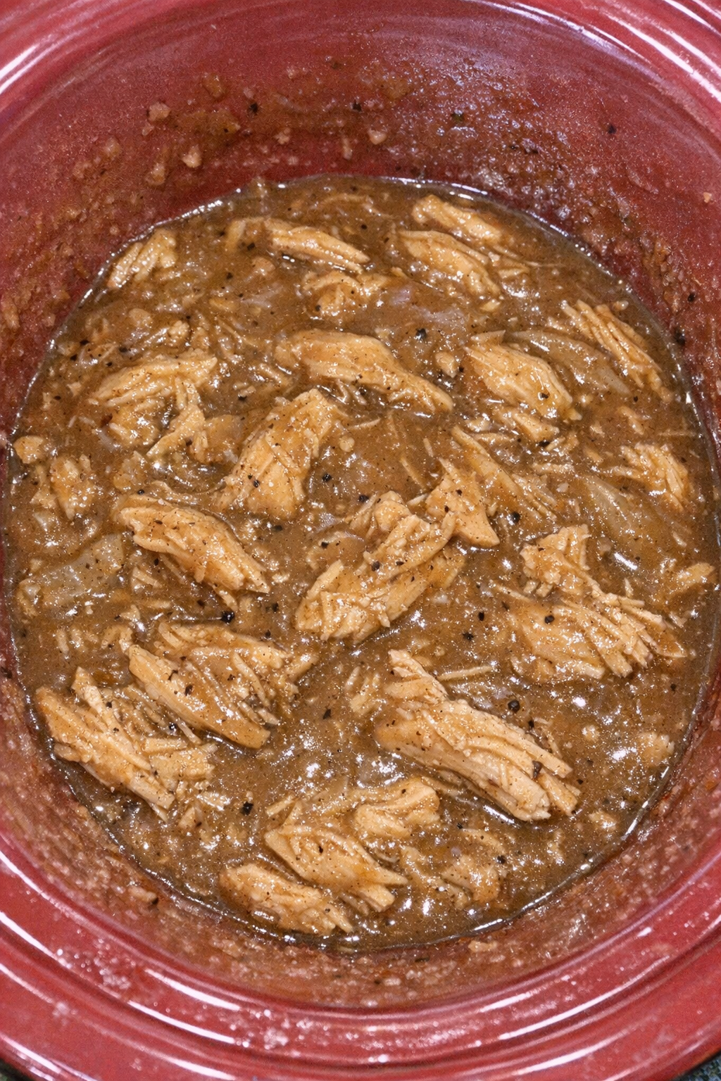 Slow cooker Amish chicken and gravy in a red slow cooker
