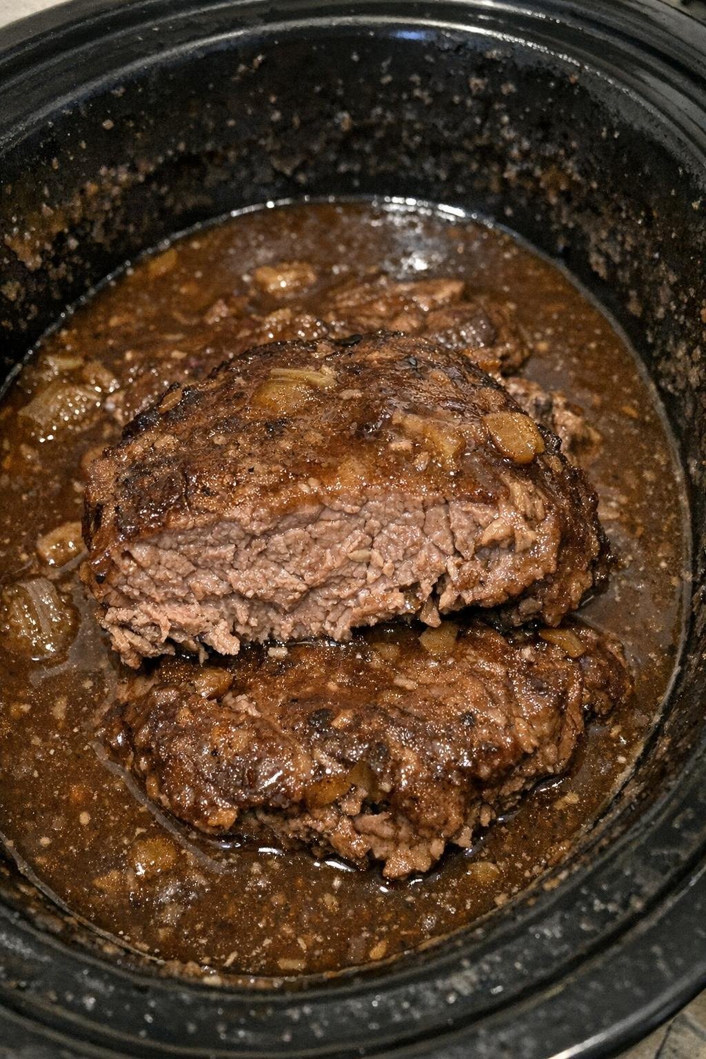 Tender round steak in rich brown gravy in a slow cooker insert