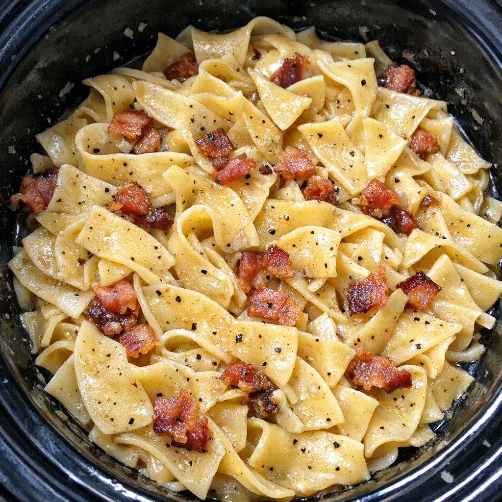 Slow cooker Amish bacon dripping noodles in a black slow cooker