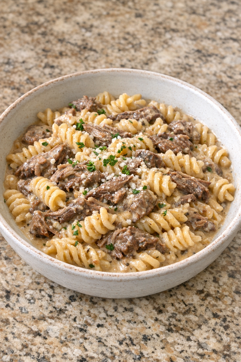 Finished creamy beef pasta plated in a rustic bowl