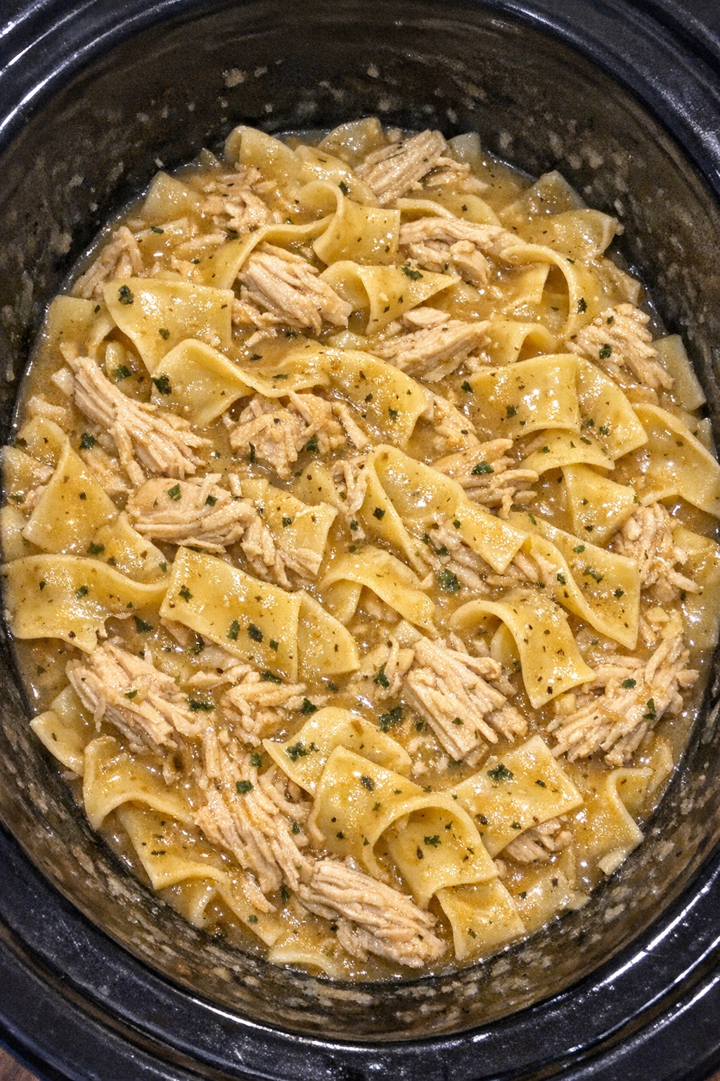 Slow cooker Amish chicken gravy noodles in a black slow cooker