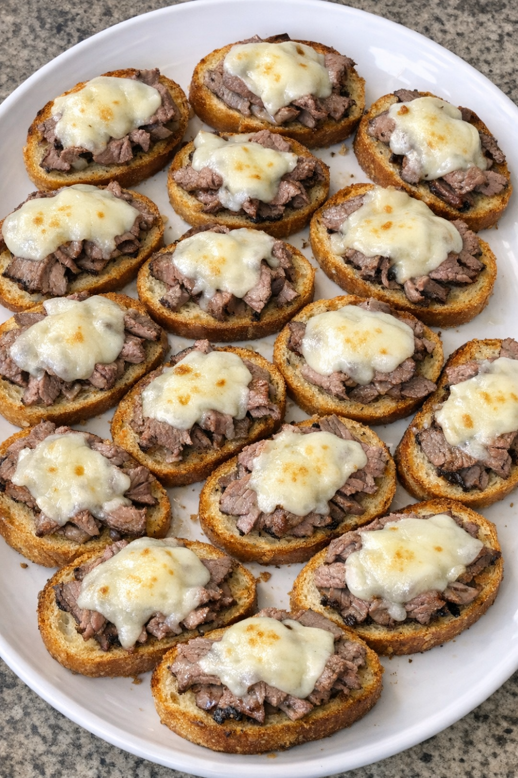 Oven baked beef crostini on a white platter