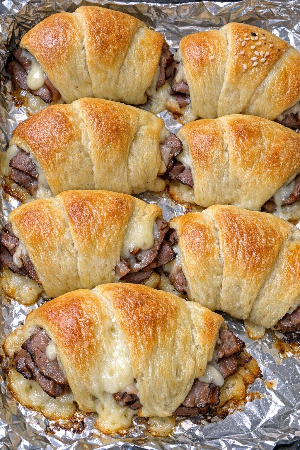 Oven baked beef French dip bundles on a foil-lined baking sheet