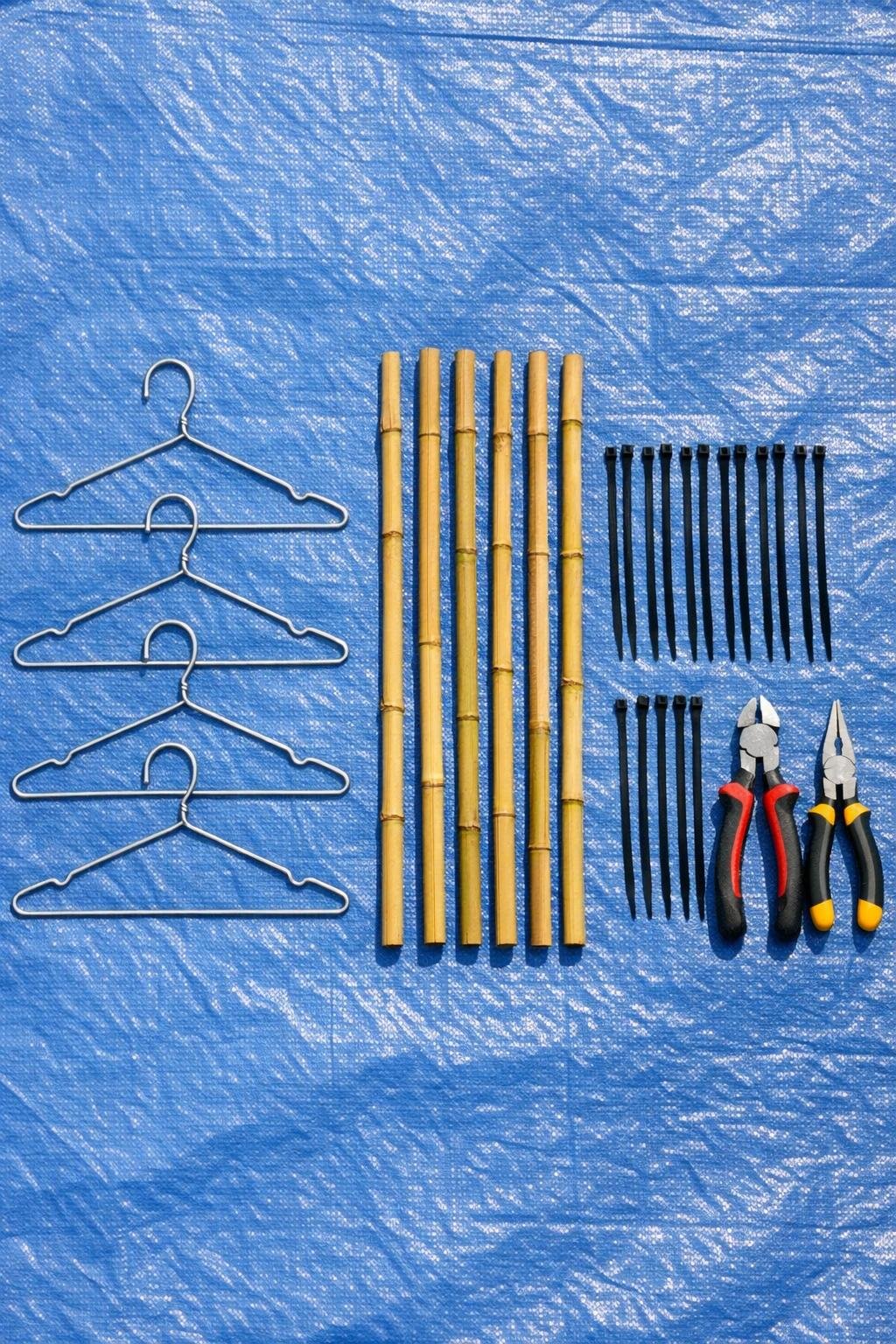 Materials for a wire coat hanger cold frame hinge system laid out on a tarp