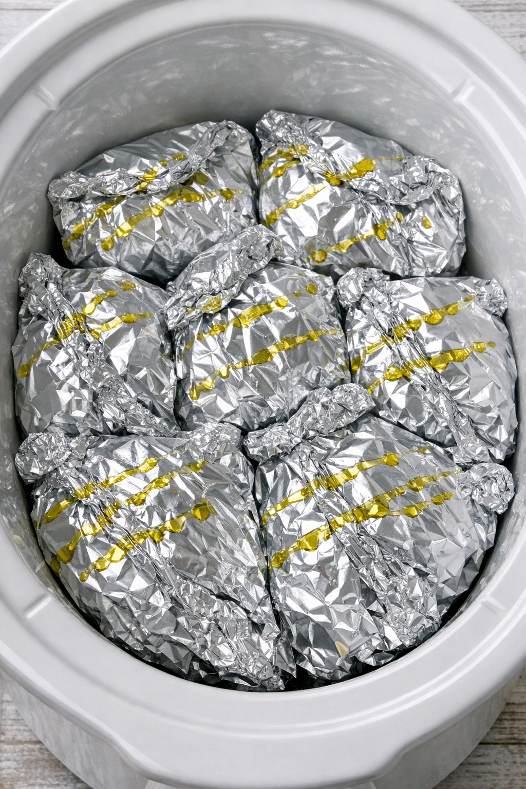 Foil-wrapped pasta packets in a white slow cooker