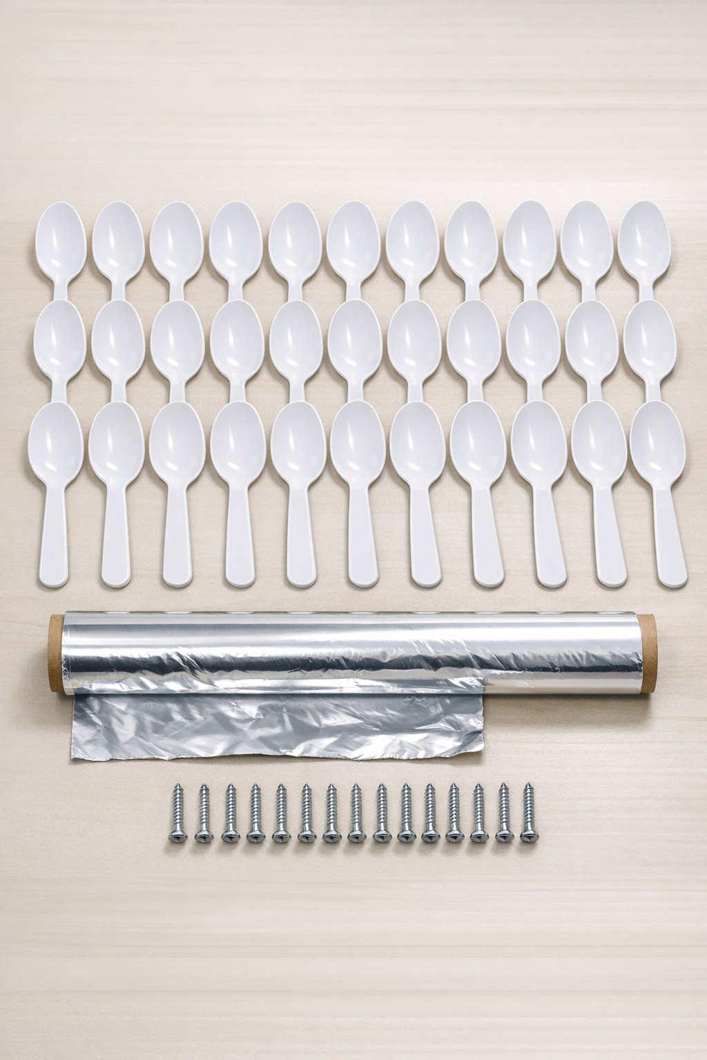 Plastic spoons, aluminum foil, and screws laid out for the project