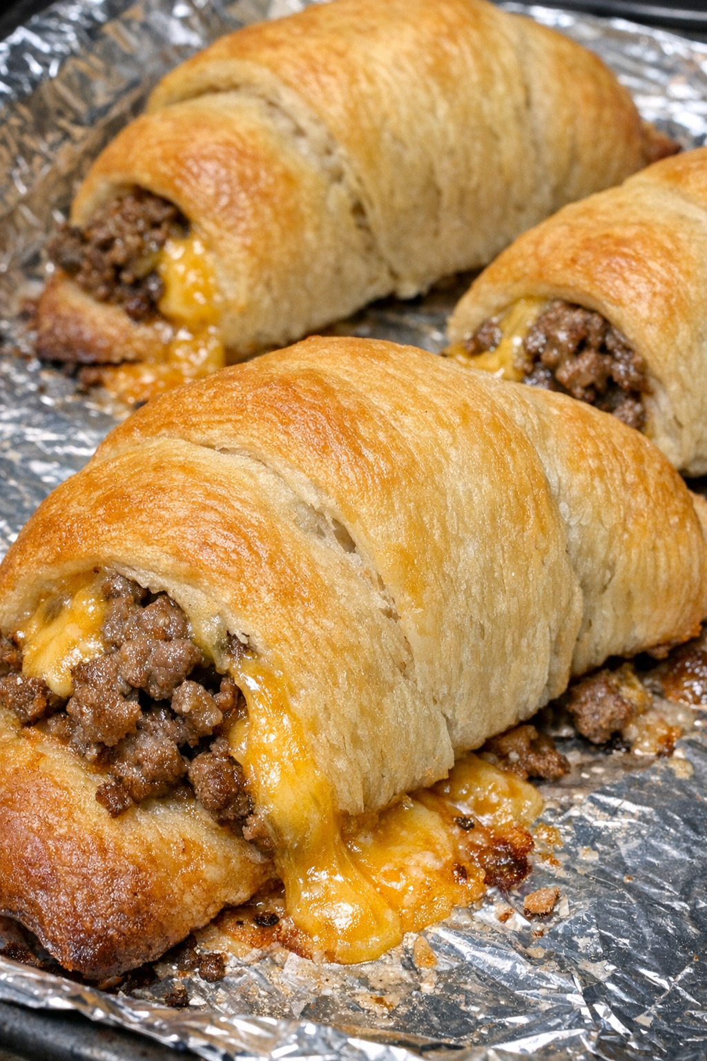 Oven baked 4-ingredient beef crescent melts on a foil-lined baking sheet