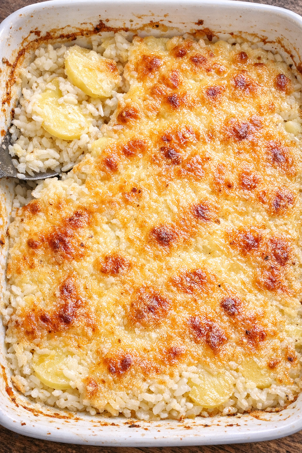 Creamy layered rice and potato casserole with a golden baked top in a white casserole dish