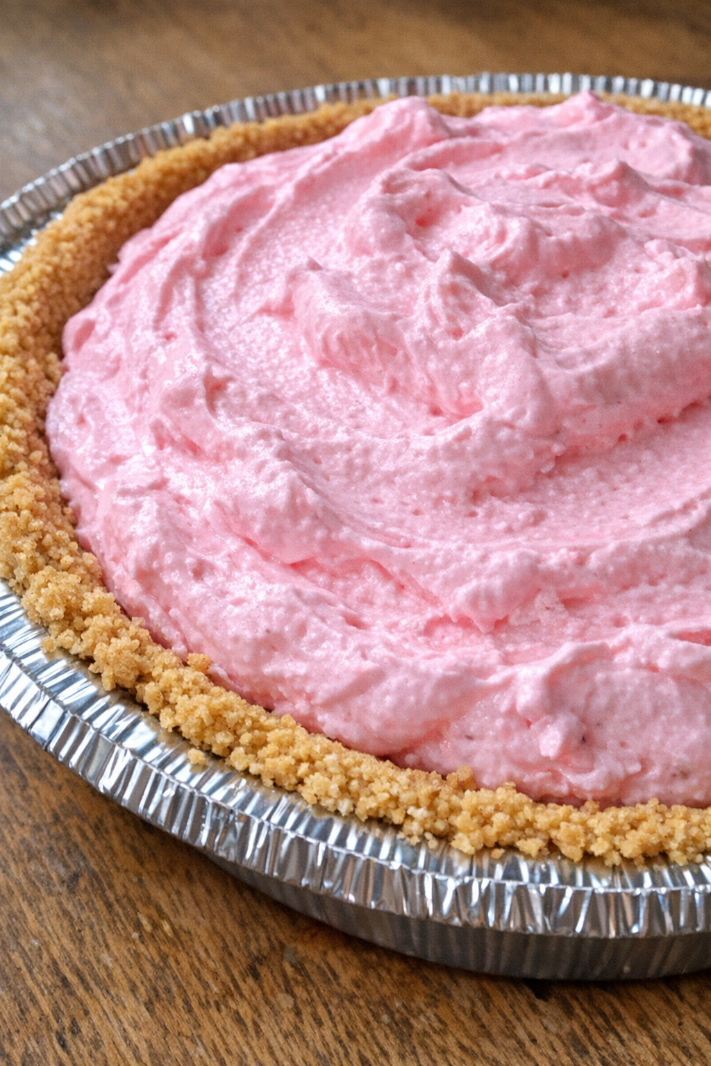 Close up of bright pink Kool-Aid pie in an aluminum pie tin