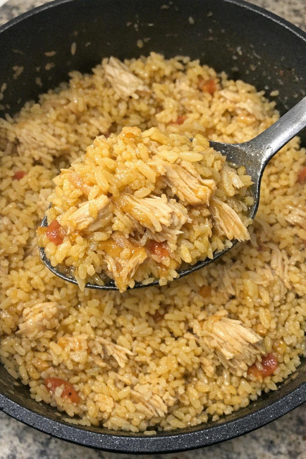 Fluffy yellow rice and shredded chicken in a black pot