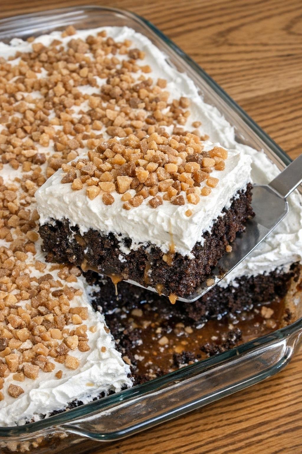 Chocolate dessert cake in a glass baking dish with whipped topping and toffee bits
