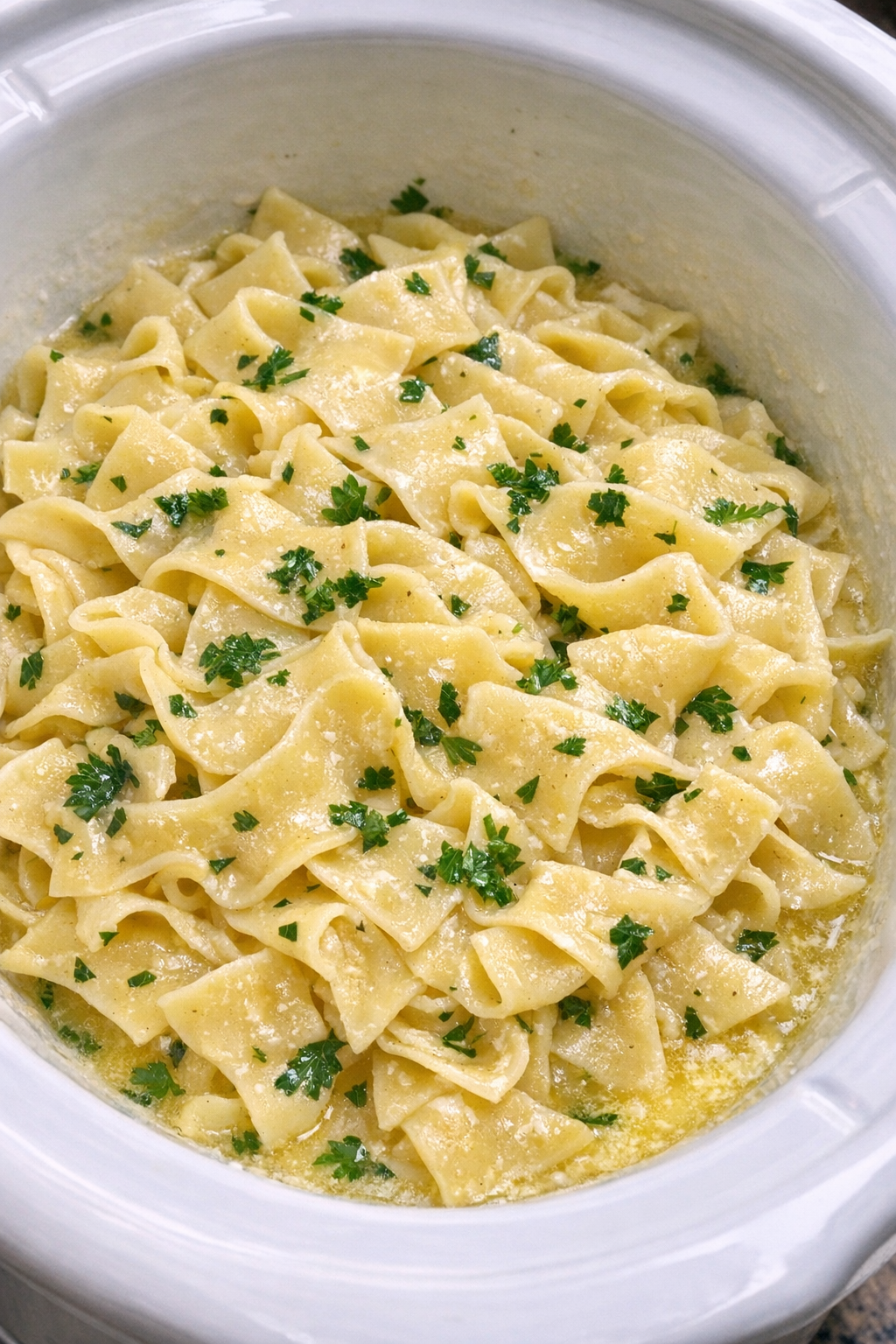 Slow cooker Amish parsley butter noodles in a white slow cooker