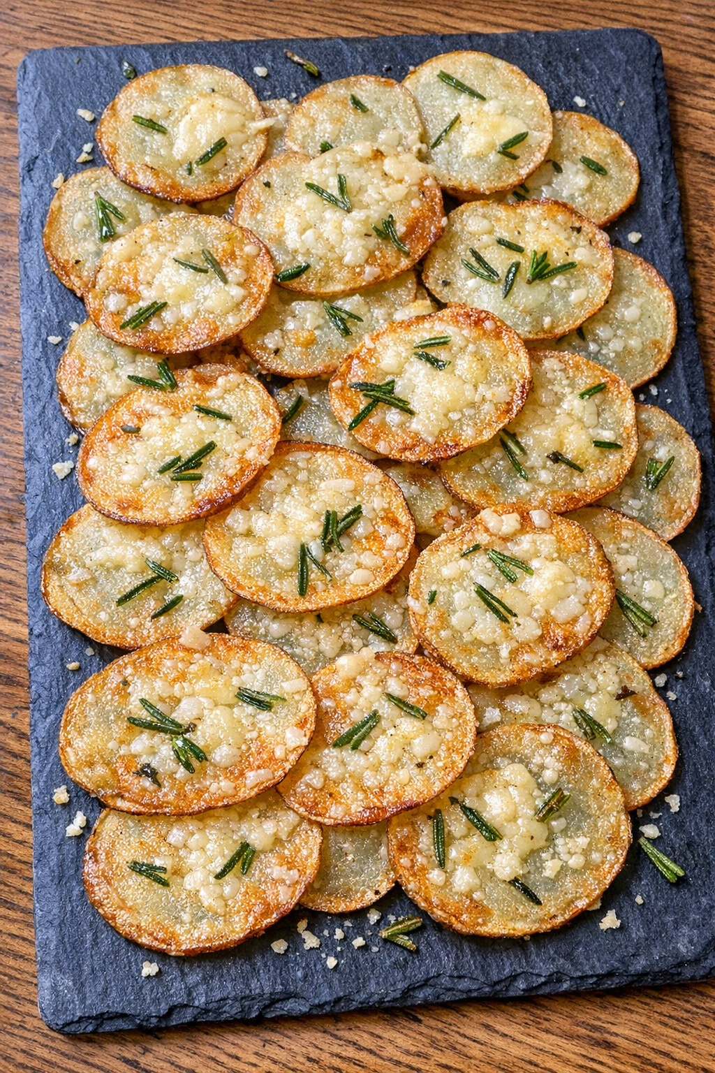 Crispy asiago rosemary potato wafers on a slate board