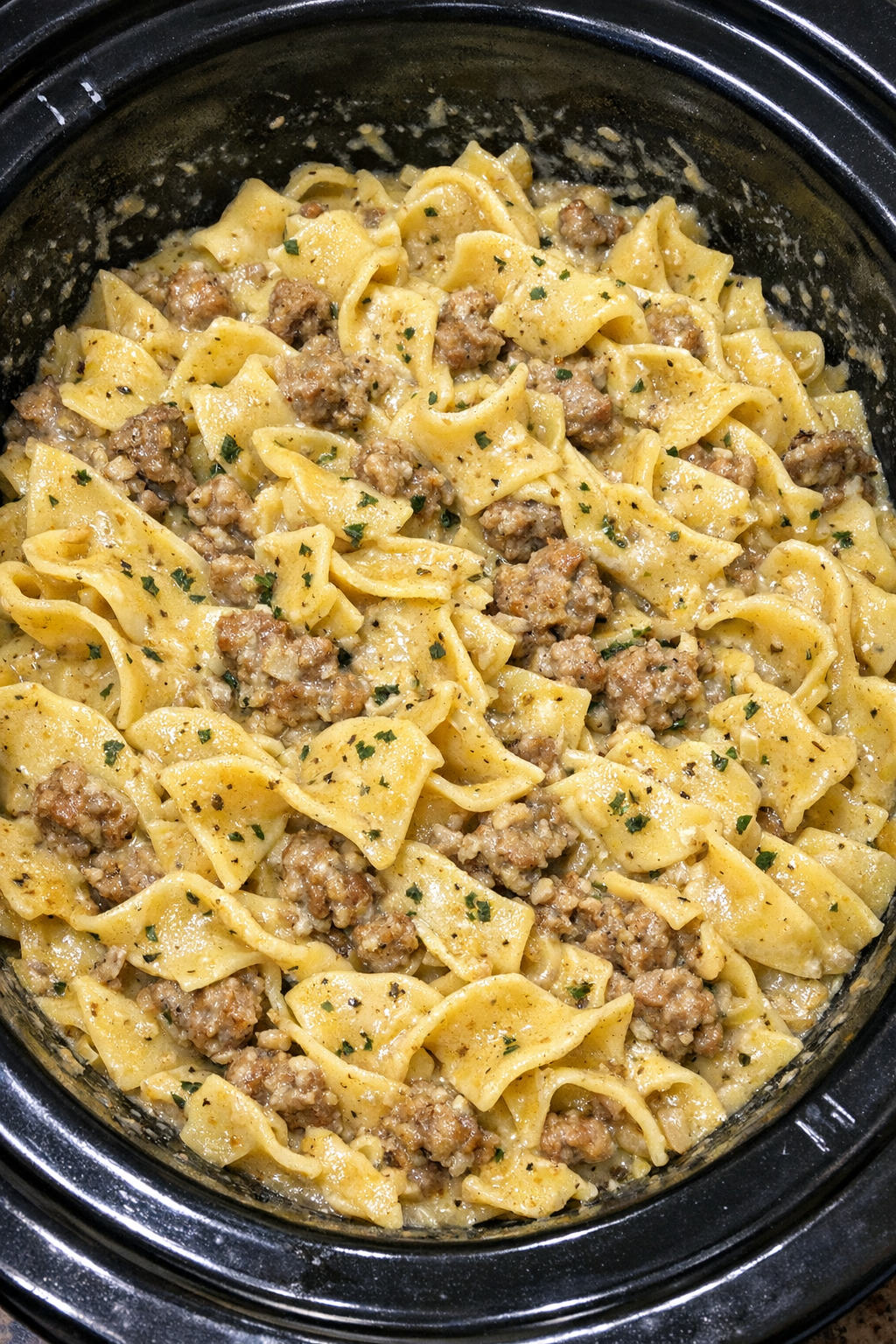Slow cooker Amish sausage noodle pot in a black slow cooker