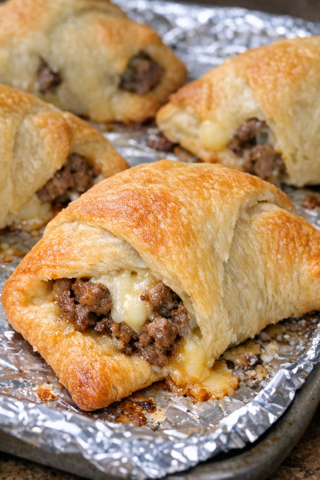 Oven baked beef crescent envelopes on a foil-lined baking sheet