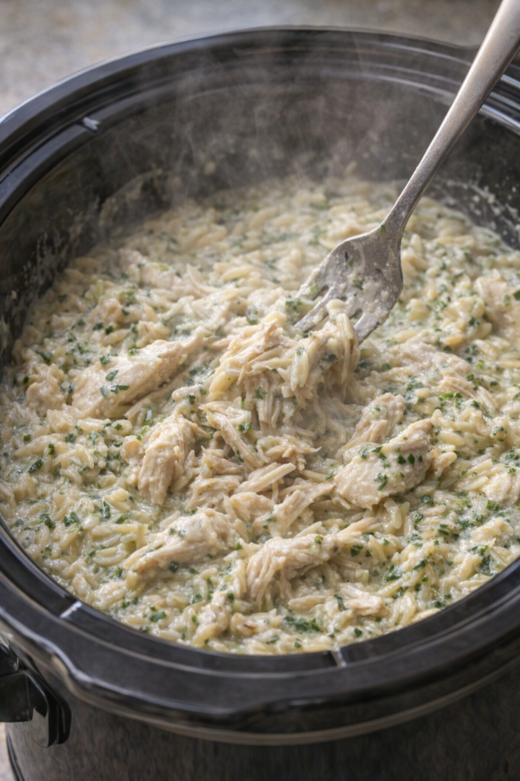 Cooked chicken and creamy orzo being stirred together