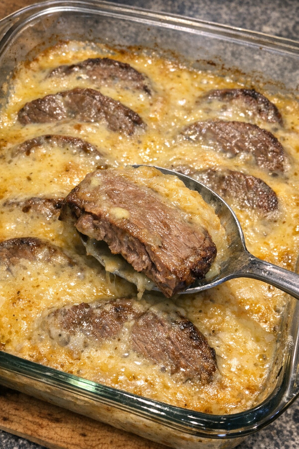 Roast beef slices in creamy golden sauce in a glass casserole dish