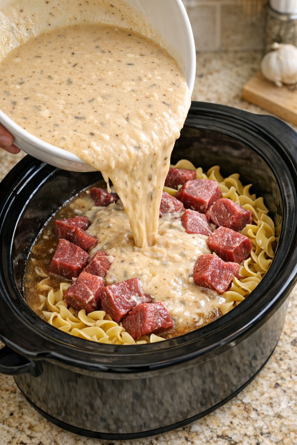 Savory broth mixture being poured over beef and noodles